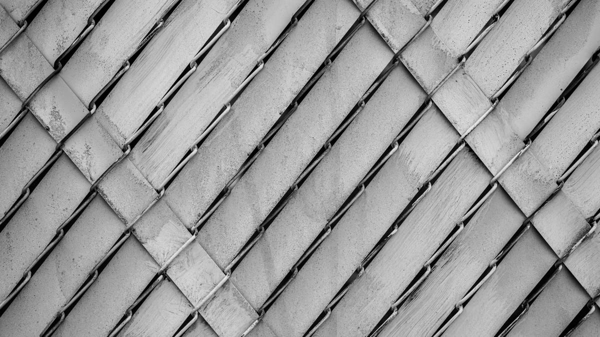 Close-up of a chain-link fence in black and white showcasing a textured pattern.
